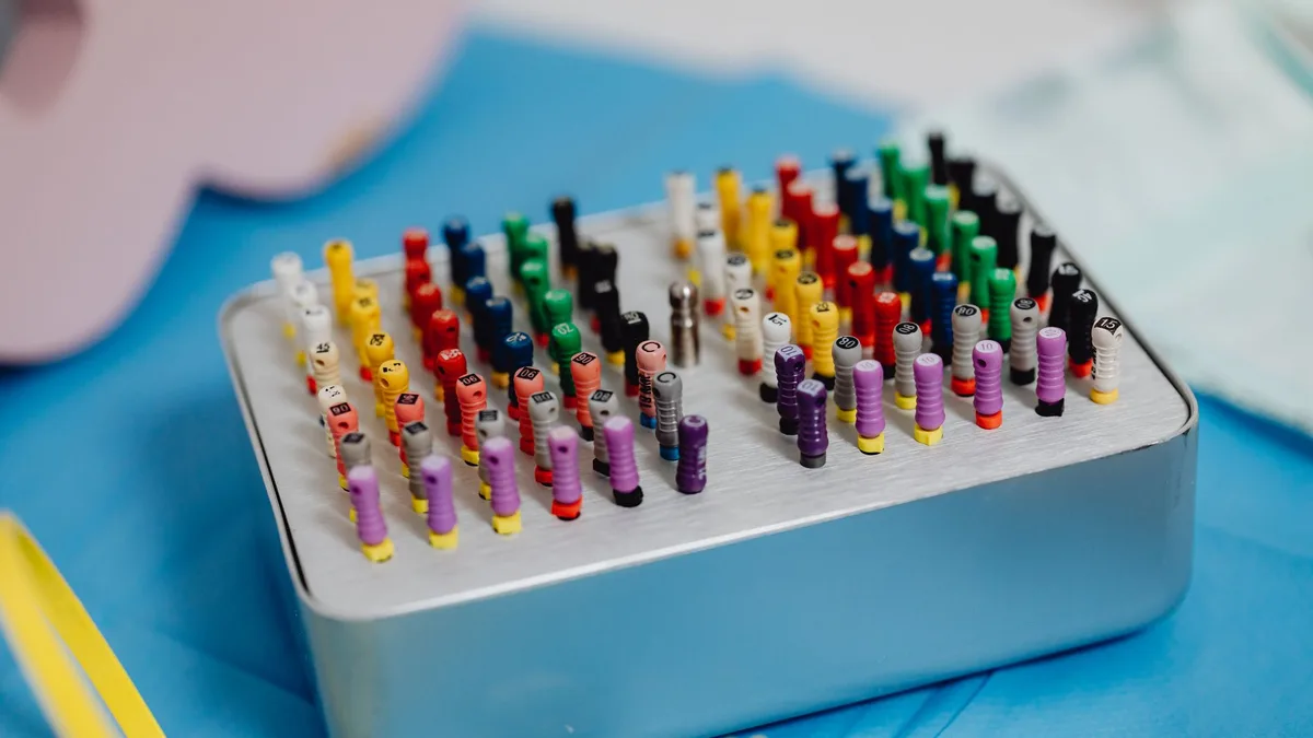 Close-up of colorful dental endodontic files arranged in a sterilization tray for dentistry use.
